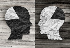 Ethnic equality concept and racial justice symbol as a black and white crumpled paper shaped as a human head on old rustic wood background with contrasting tones as a metaphor for social race issues.